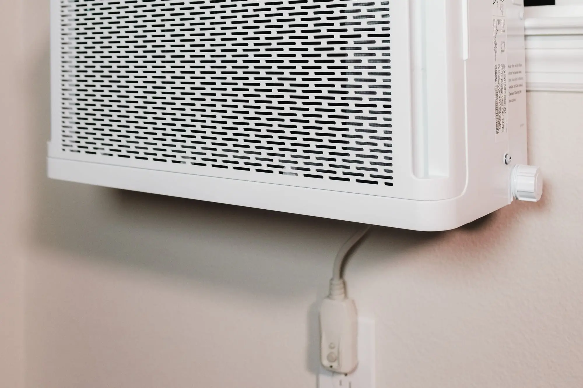 A white window air conditioning unit mounted on a wall in a house