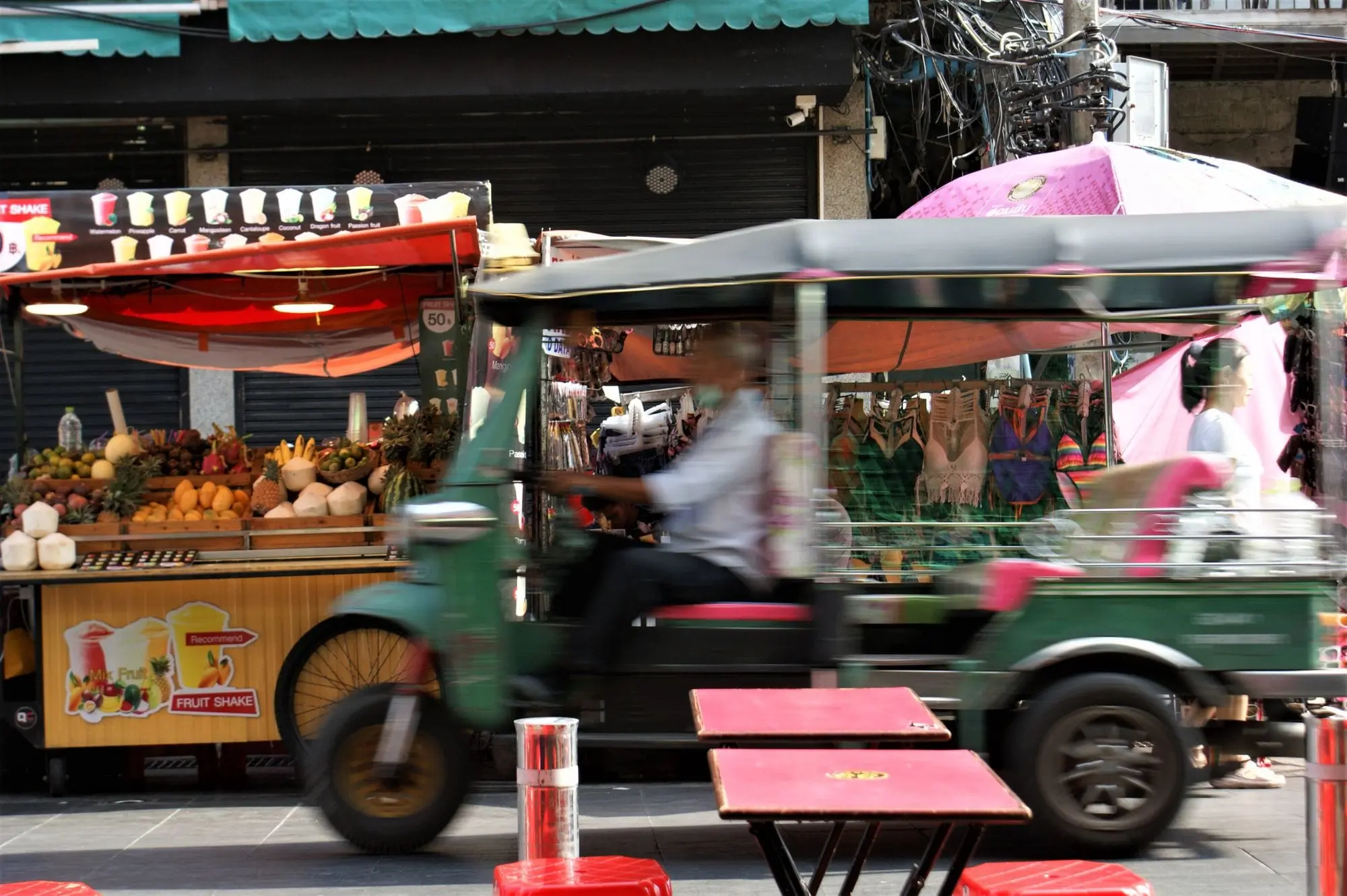 Tuk-tuk passing a street food stall in Bangkok