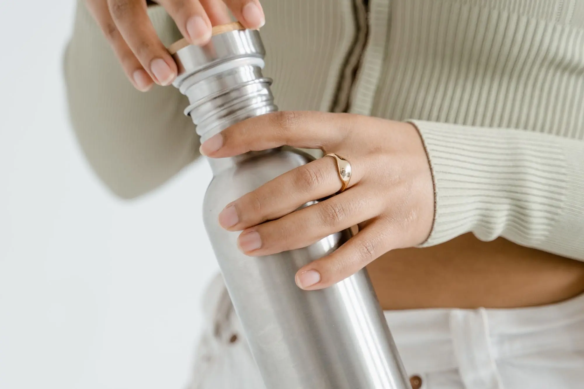 Hands closing the lid of a stainless steel reusable water bottle