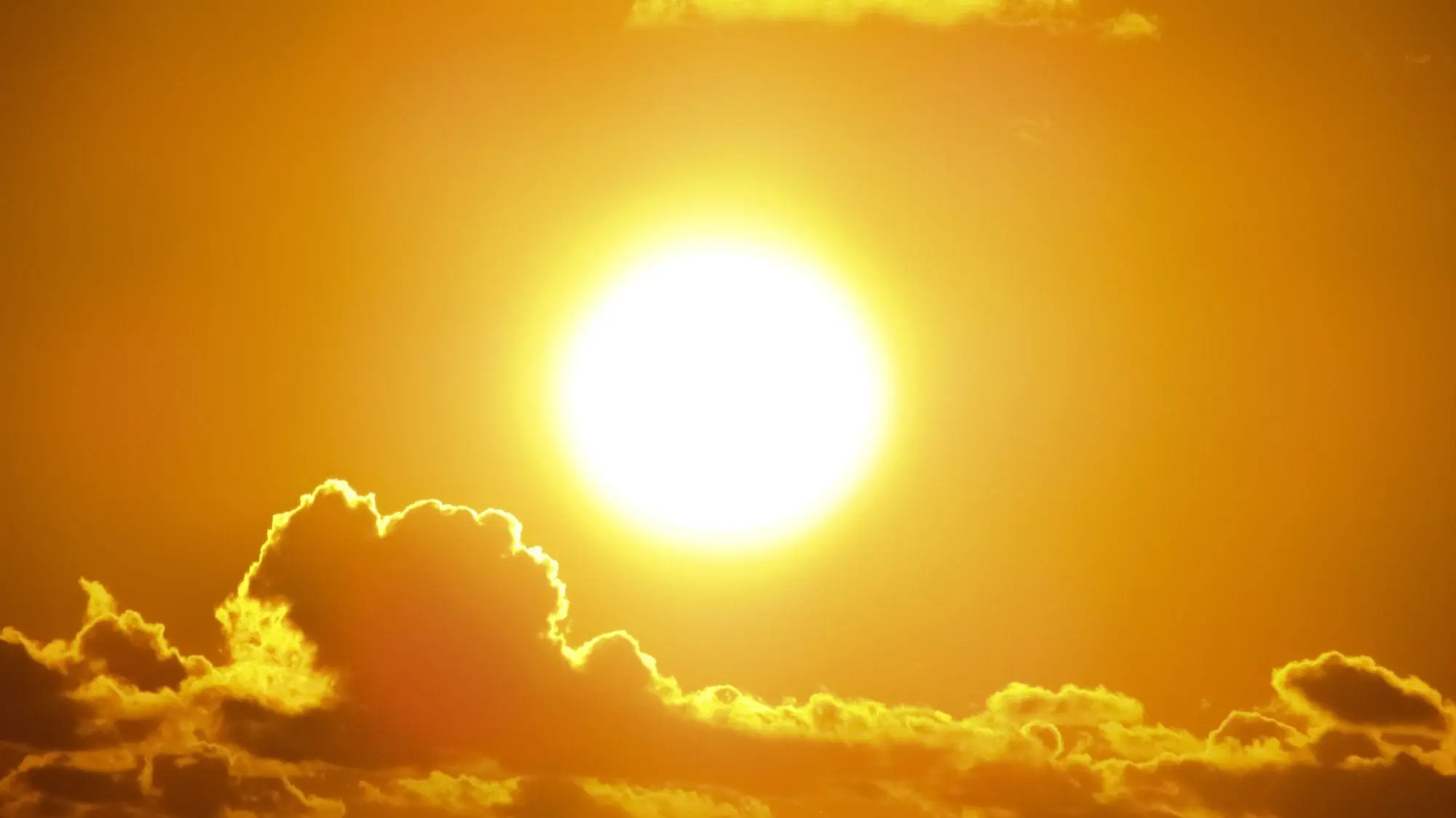 Blazing sun over clouds in an orange sky