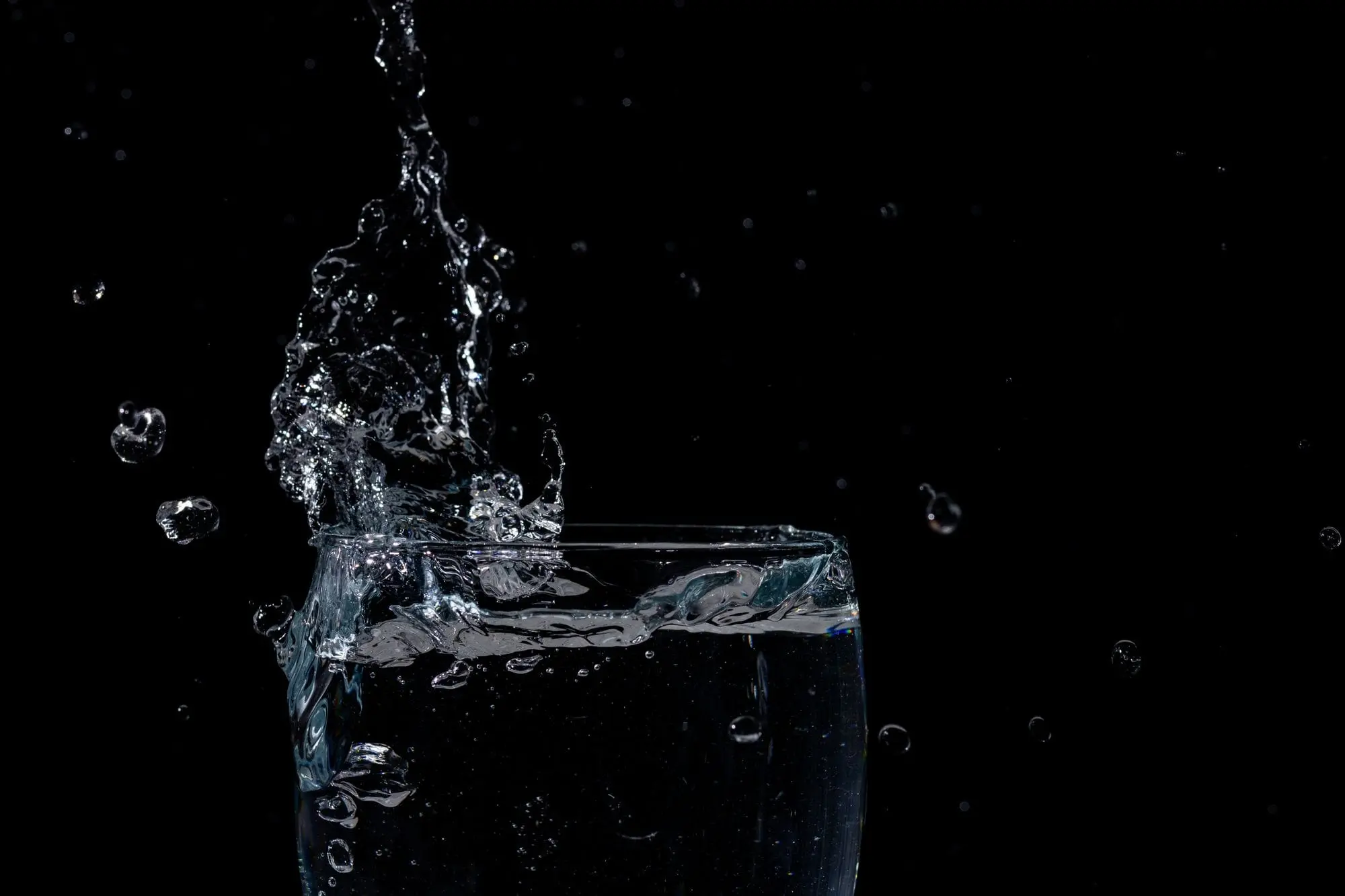 Water splashing out of a glass against a black background
