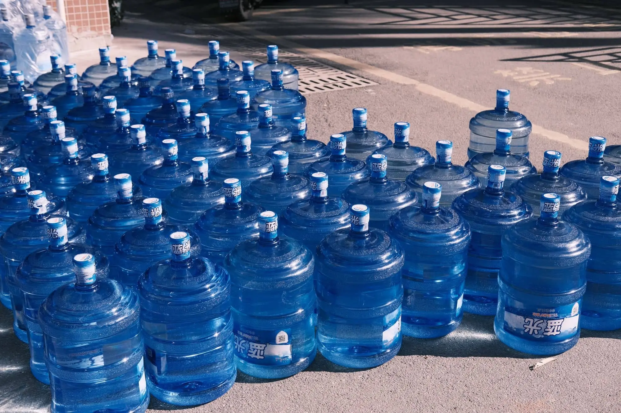 Rows of blue plastic water jugs lined up on a street