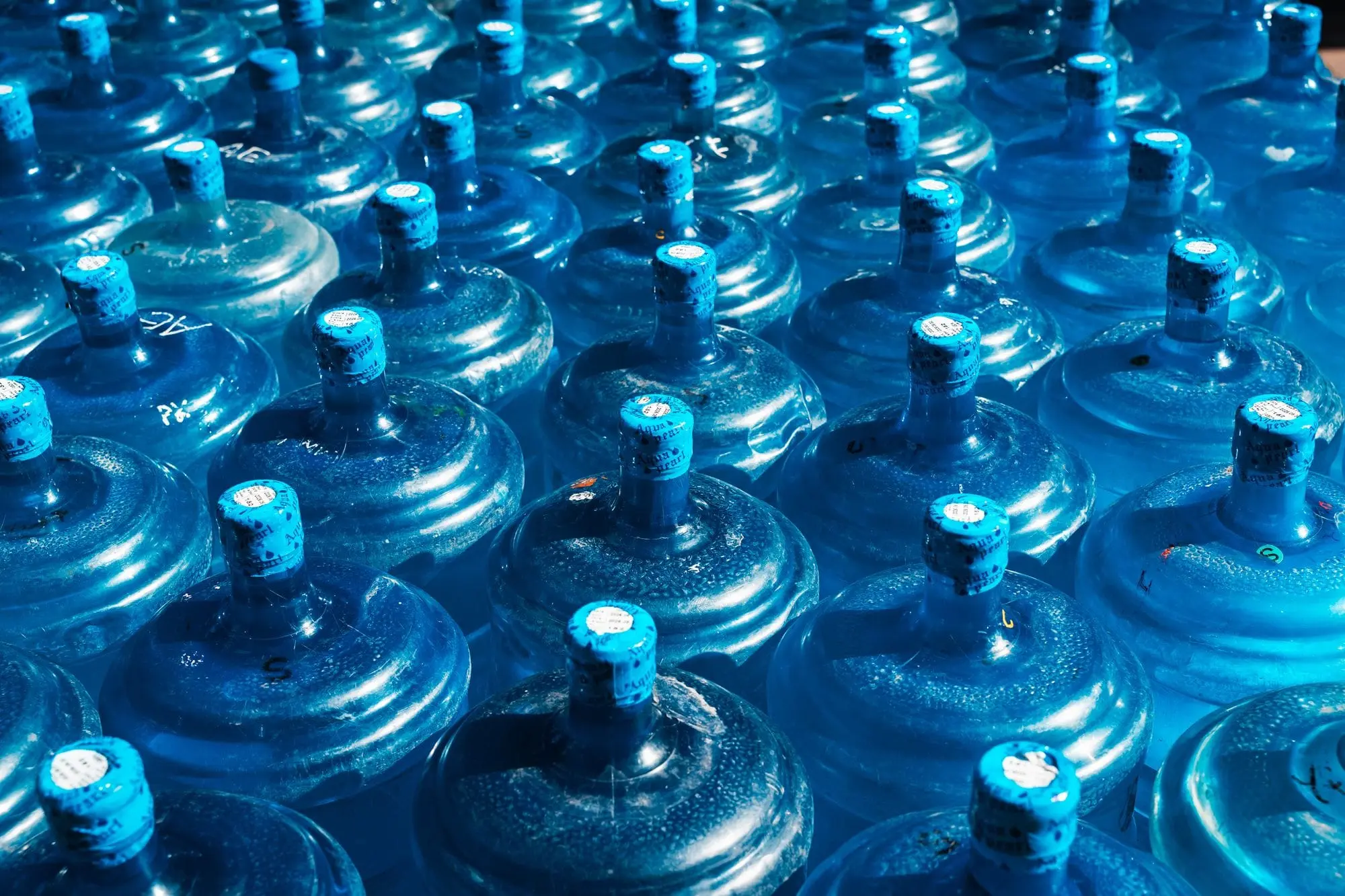Stacks of blue 20-litre water bottles seen from above