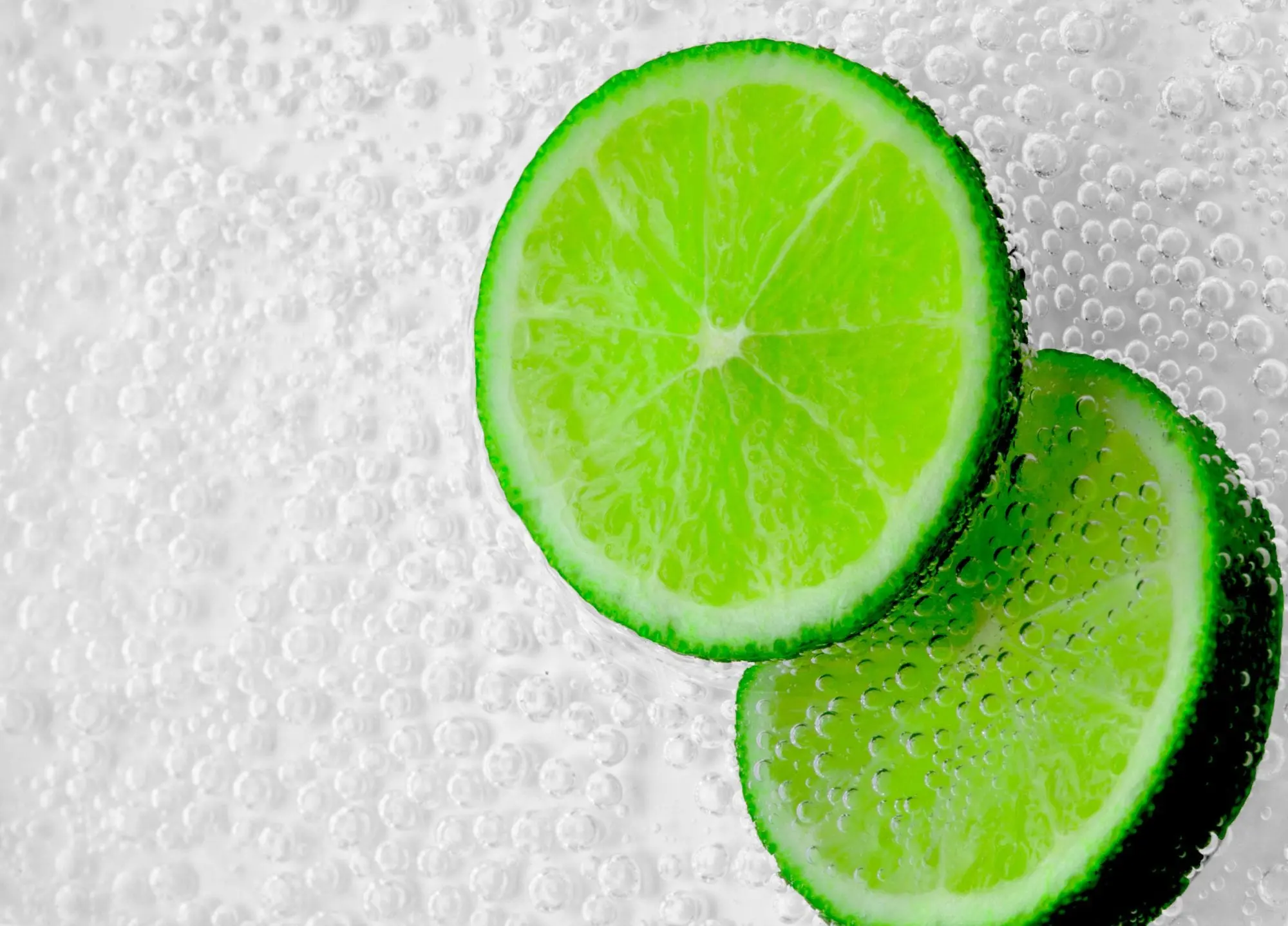 Two lime slices in a glass of sparkling water full of fine bubbles