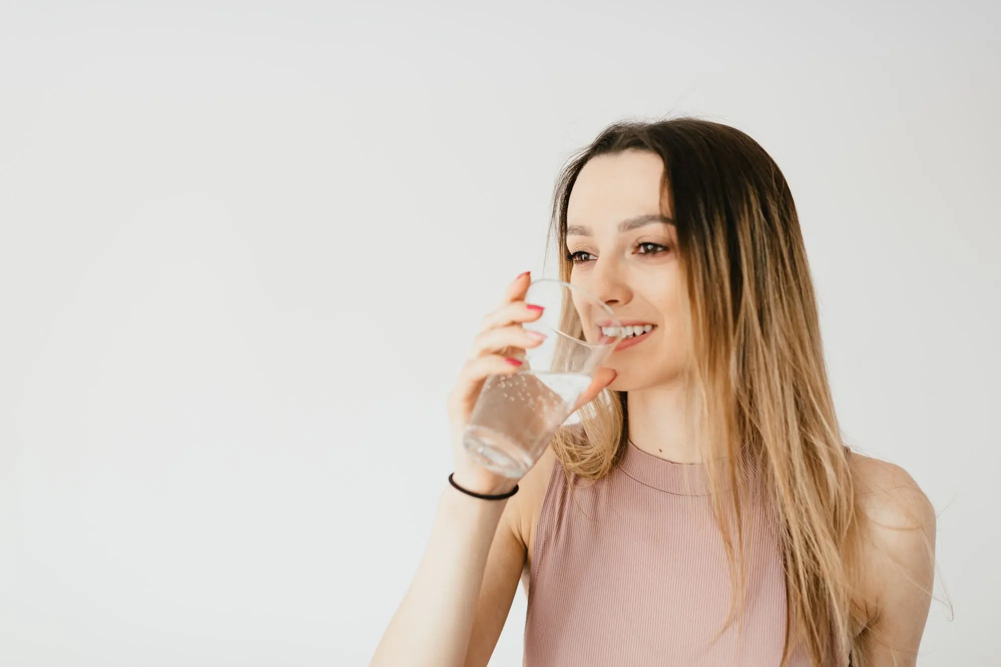 Smiling young woman drinking a glass of water