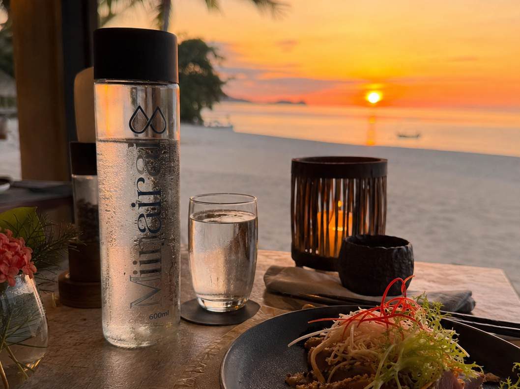 A Minairal glass bottle on a restaurant table by the beach